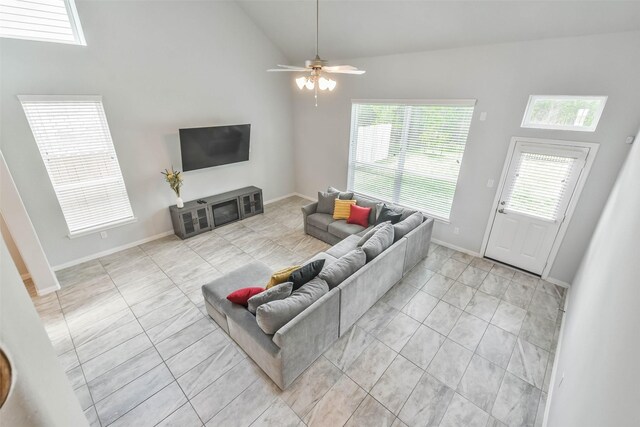 tiled living room with ceiling fan and high vaulted ceiling