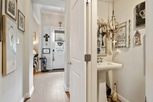 corridor with sink, hardwood / wood-style flooring, and ornamental molding