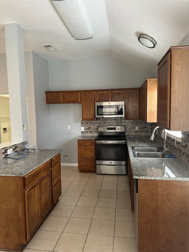 kitchen featuring stainless steel appliances, sink, light tile patterned floors, decorative backsplash, and lofted ceiling