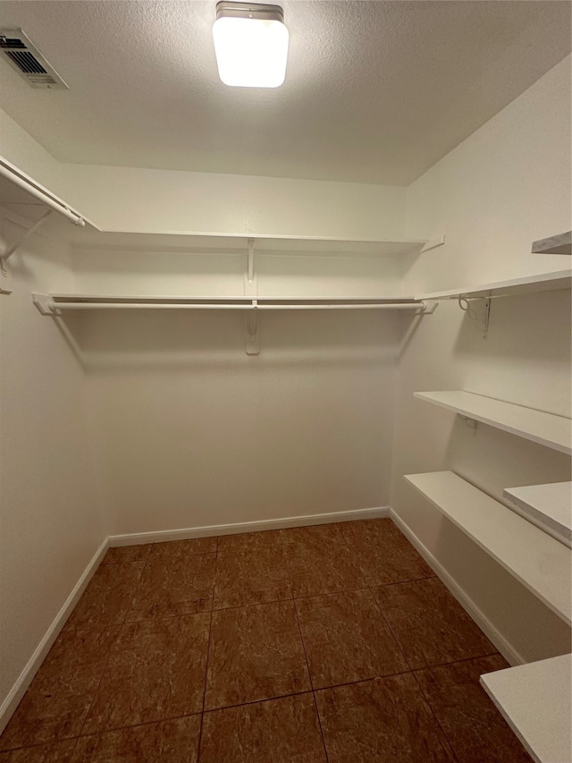 spacious closet featuring dark tile patterned floors