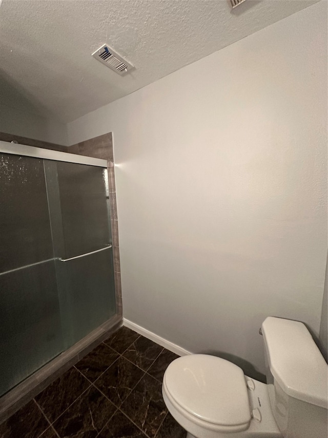 bathroom featuring toilet, tile patterned floors, a textured ceiling, and an enclosed shower