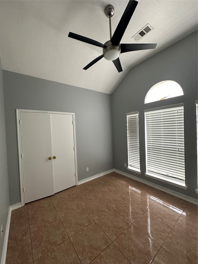 tiled spare room featuring vaulted ceiling and ceiling fan