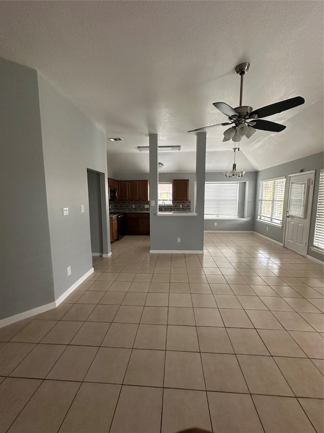 unfurnished living room with lofted ceiling, a textured ceiling, light tile patterned floors, and ceiling fan