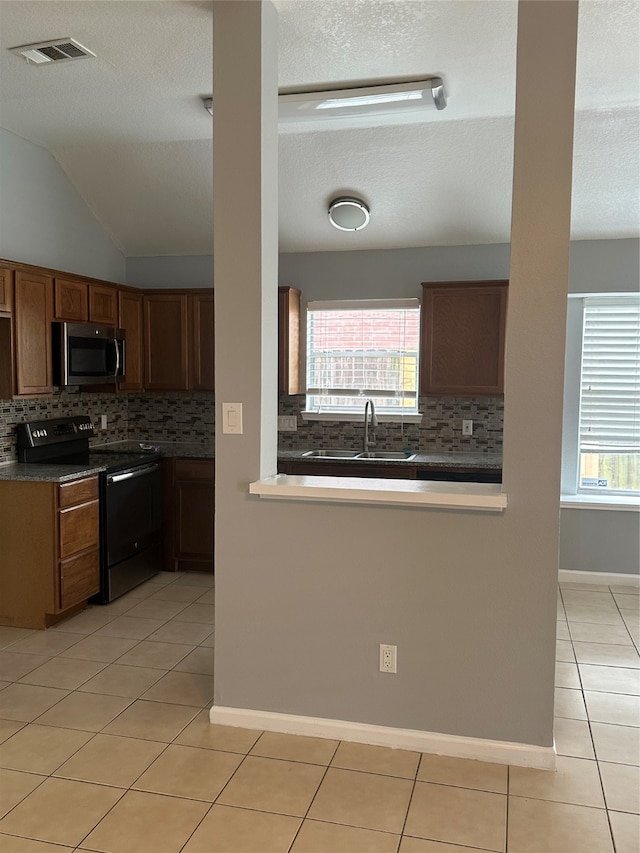 kitchen with light tile patterned flooring, sink, black range with electric stovetop, and backsplash