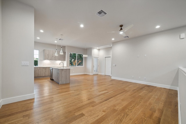 unfurnished living room featuring light hardwood / wood-style flooring, sink, and ceiling fan