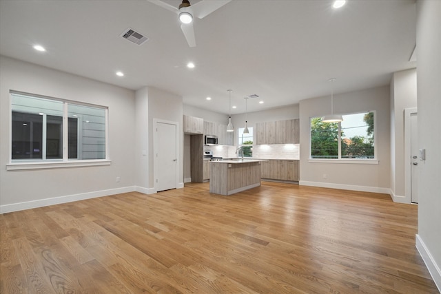 unfurnished living room with light hardwood / wood-style floors, sink, and ceiling fan