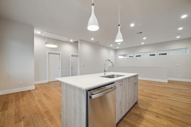 kitchen with pendant lighting, sink, dishwasher, a center island with sink, and light hardwood / wood-style flooring