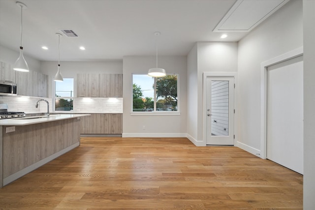 kitchen featuring hanging light fixtures, stove, tasteful backsplash, and light wood-type flooring