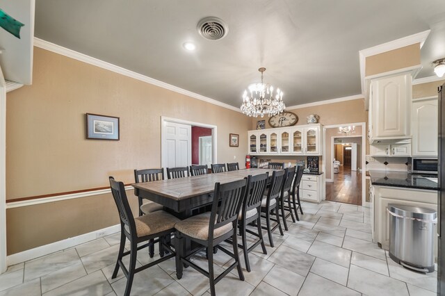 dining area with crown molding, light tile patterned floors, and an inviting chandelier