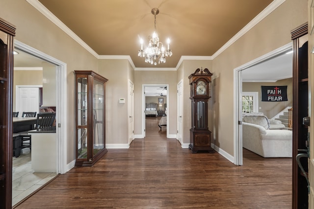 foyer entrance with dark hardwood / wood-style flooring, ornamental molding, and an inviting chandelier