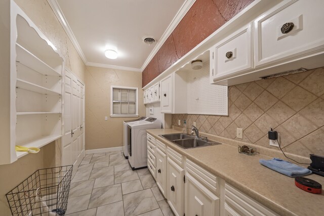 kitchen featuring tasteful backsplash, crown molding, independent washer and dryer, white cabinetry, and sink