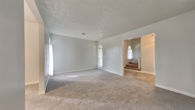 carpeted empty room with a textured ceiling