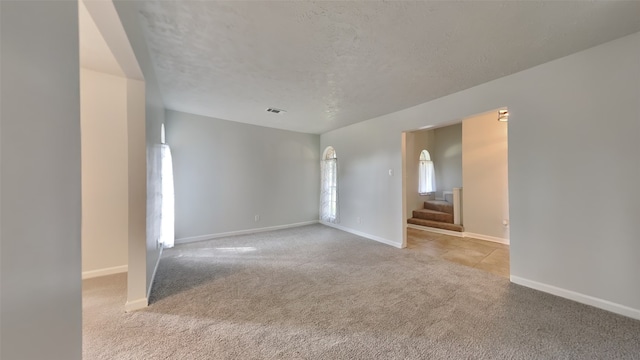 spare room with light colored carpet and a textured ceiling