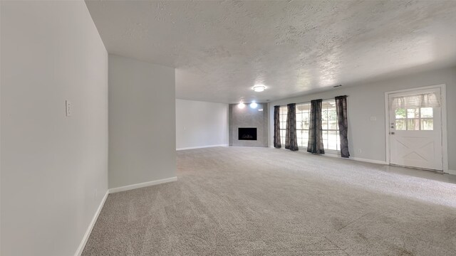 unfurnished living room with a textured ceiling, carpet floors, and a fireplace