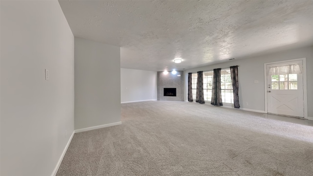 unfurnished living room with carpet floors, a large fireplace, and a textured ceiling