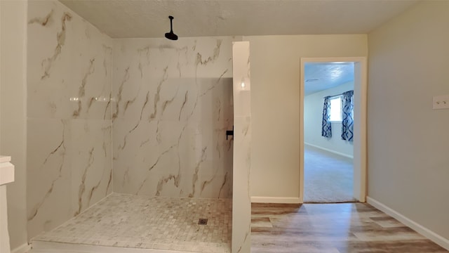 bathroom featuring tiled shower, a textured ceiling, and hardwood / wood-style flooring