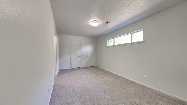 carpeted empty room featuring a textured ceiling