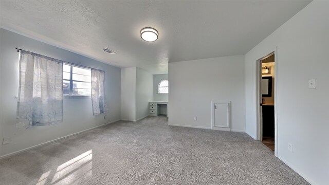 unfurnished bedroom with ensuite bathroom, carpet floors, and a textured ceiling