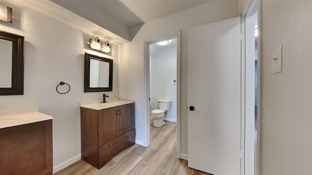 bathroom with toilet, wood-type flooring, and double sink vanity