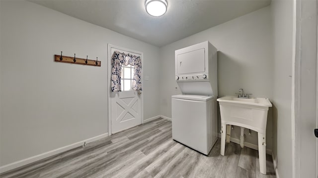 laundry room with stacked washing maching and dryer and light hardwood / wood-style floors