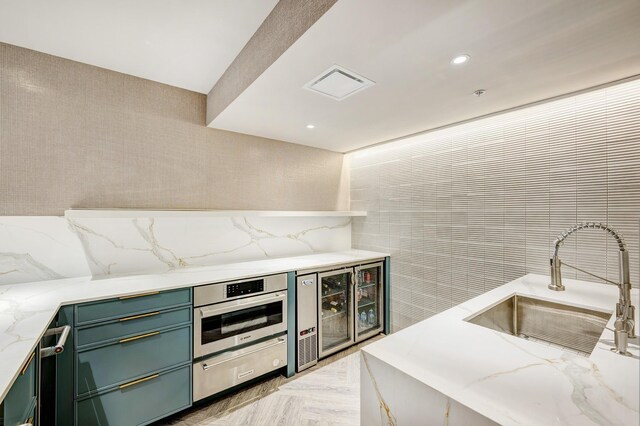 kitchen featuring sink, light stone counters, stainless steel oven, light parquet flooring, and beverage cooler