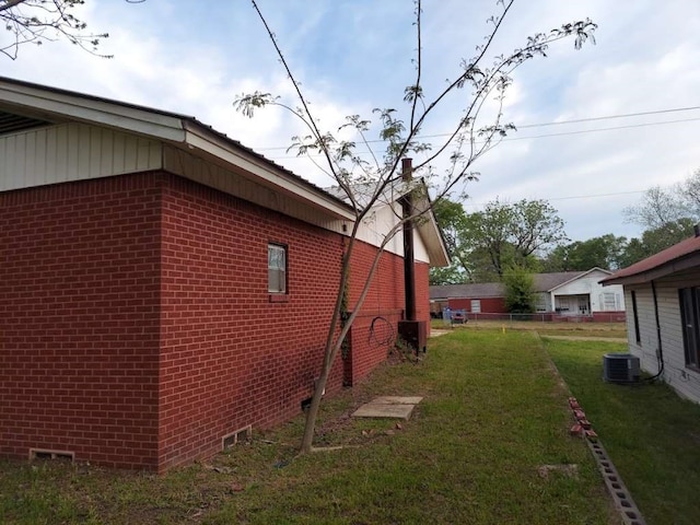 view of side of home featuring central AC unit and a yard