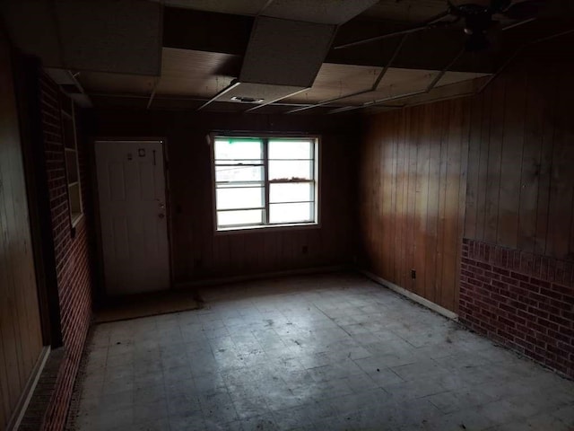 unfurnished room with tile patterned flooring, wood walls, and ceiling fan