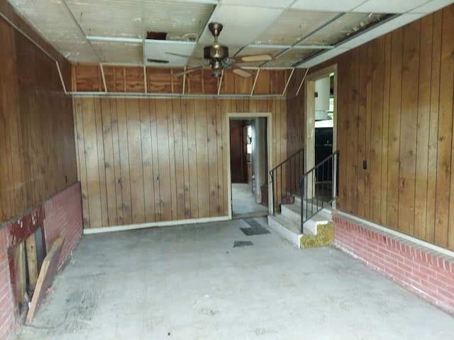 basement featuring wood walls and ceiling fan