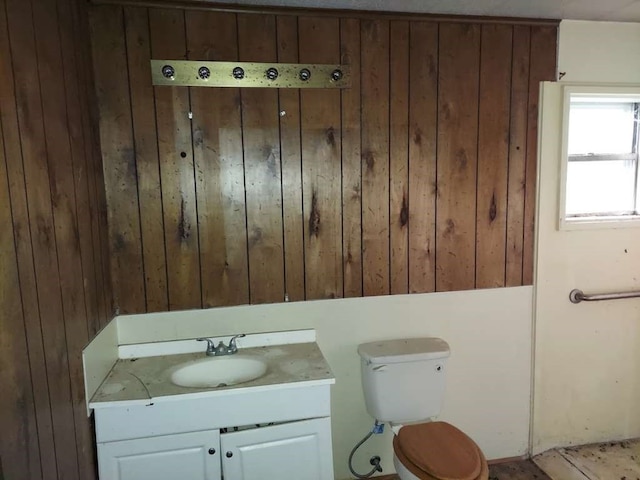 bathroom featuring vanity, toilet, and wooden walls