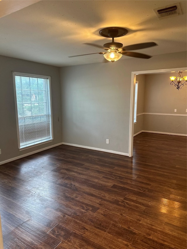 empty room with ceiling fan with notable chandelier and hardwood / wood-style flooring