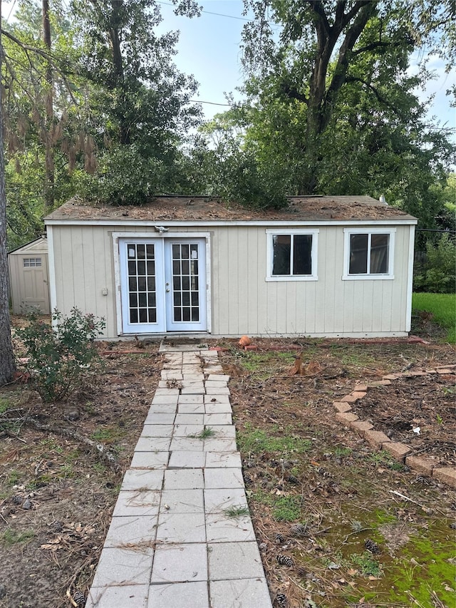 rear view of property featuring an outdoor structure and french doors