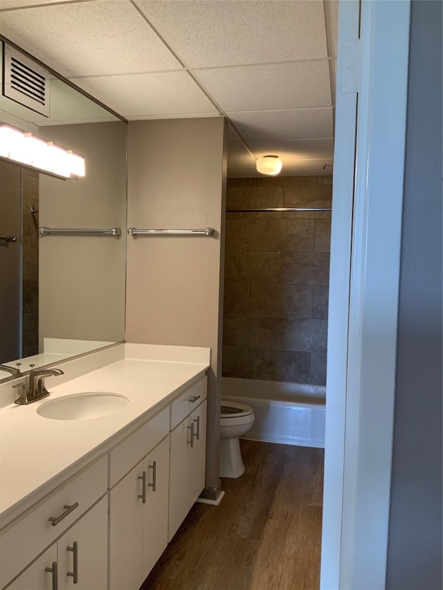 full bathroom featuring vanity, wood-type flooring, washtub / shower combination, a paneled ceiling, and toilet