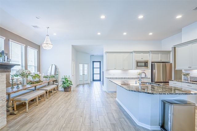 kitchen with sink, dark stone countertops, black microwave, stainless steel refrigerator, and backsplash