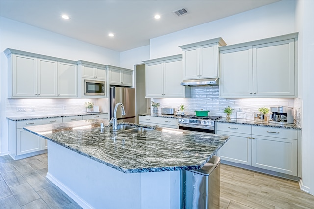 kitchen with backsplash, appliances with stainless steel finishes, and a center island with sink