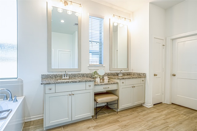 bathroom with a bath and dual bowl vanity