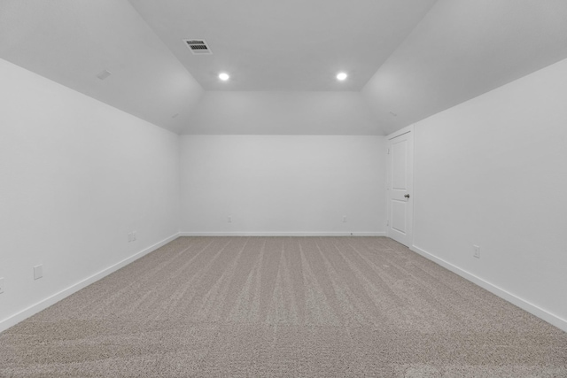 carpeted empty room featuring vaulted ceiling