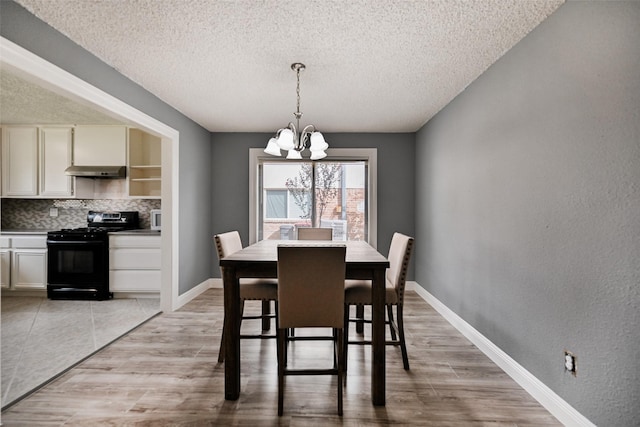 dining space featuring a textured ceiling, light hardwood / wood-style floors, and a chandelier