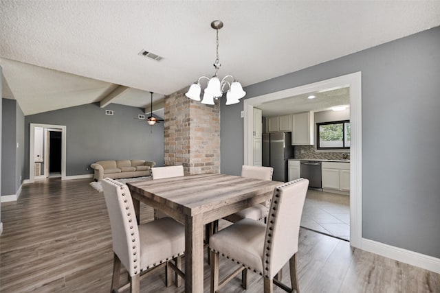 dining space featuring vaulted ceiling with beams, ceiling fan with notable chandelier, wood-type flooring, and a textured ceiling