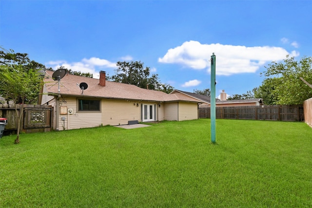 back of house with french doors and a yard