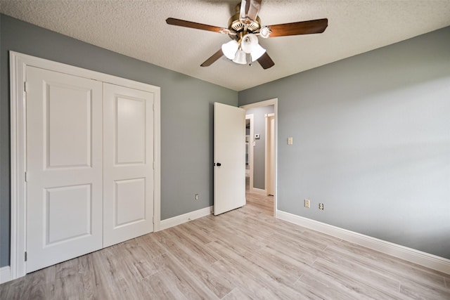 unfurnished bedroom with ceiling fan, light hardwood / wood-style floors, a closet, and a textured ceiling