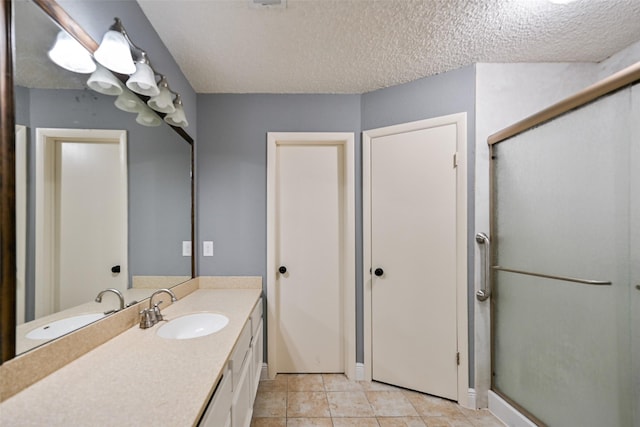 bathroom with a shower with door, vanity, and a textured ceiling