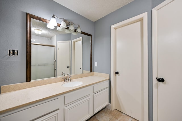 bathroom featuring a shower with door, vanity, tile patterned floors, and a textured ceiling