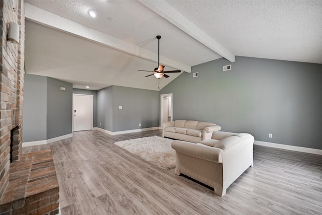 living room featuring a textured ceiling, a fireplace, lofted ceiling with beams, and wood-type flooring