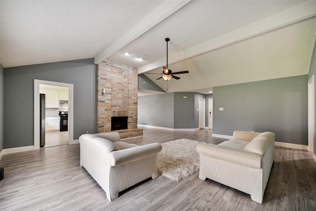 living room with ceiling fan, lofted ceiling with beams, a brick fireplace, and light hardwood / wood-style flooring