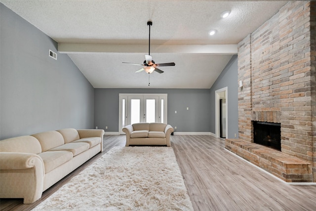 unfurnished living room featuring vaulted ceiling with beams, hardwood / wood-style flooring, a fireplace, and french doors