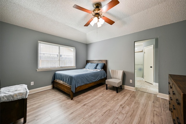 bedroom featuring a textured ceiling, vaulted ceiling, light hardwood / wood-style floors, and ceiling fan