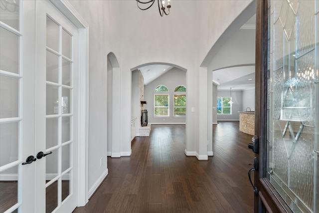 foyer entrance with an inviting chandelier, vaulted ceiling, and dark hardwood / wood-style floors