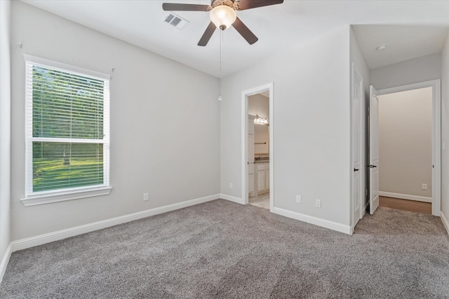 unfurnished bedroom featuring light carpet, ensuite bath, and ceiling fan