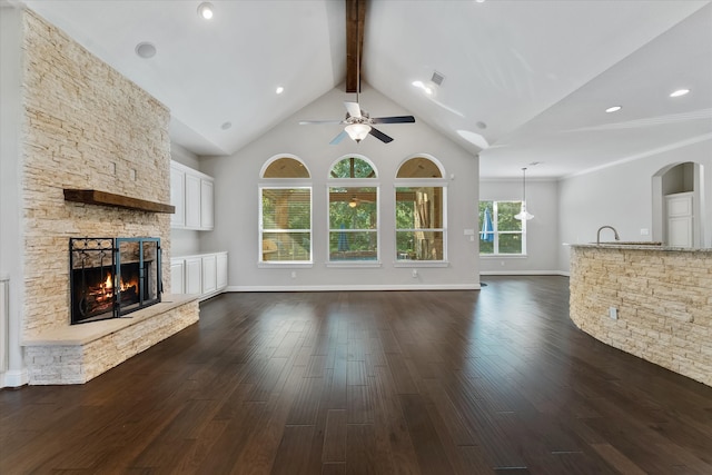 unfurnished living room with beamed ceiling, dark hardwood / wood-style floors, a fireplace, high vaulted ceiling, and ceiling fan