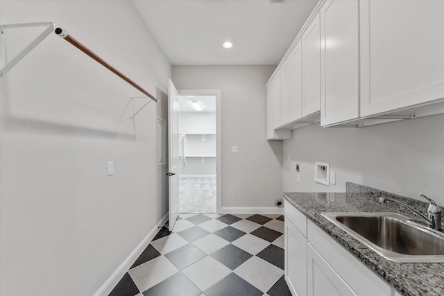 kitchen featuring white cabinets, dark stone counters, and sink